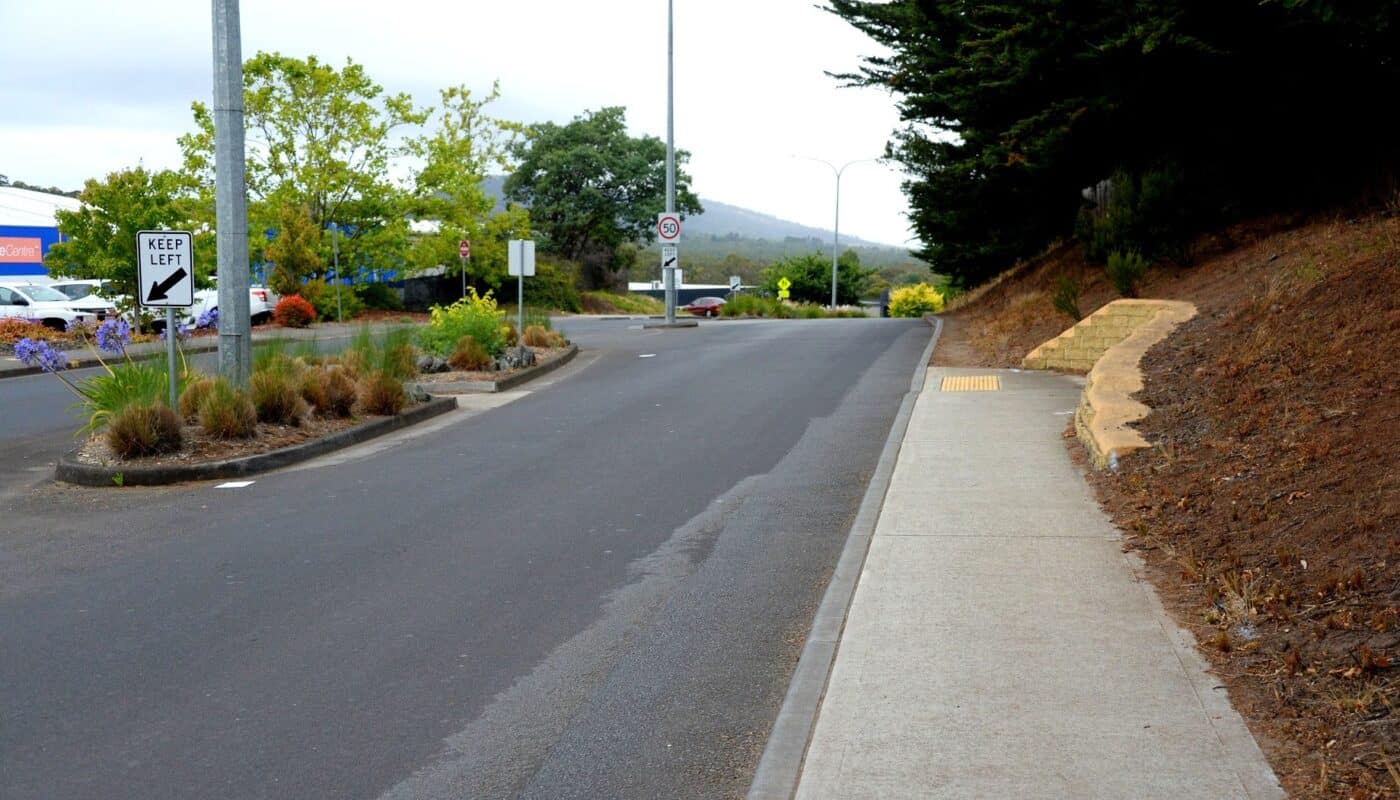 A concrete footpath on the right of the image ends in a culvert painted yellow, with the pedestrian median obvious on the left of the image. 