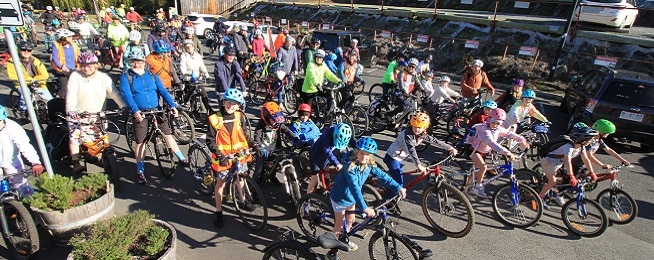 Large group of younger and older riders poses in the car park between the end of the Hobart Rivulet Path and Molle Street.