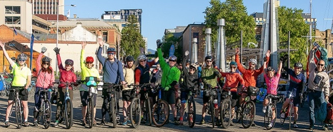 Line of people holding bikes with some raising their hands in the air.