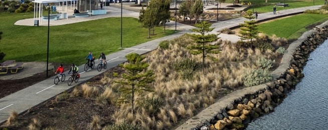 Aerial view of four people ride along the Clarence Foreshore Trail around Kangaroo Bay.